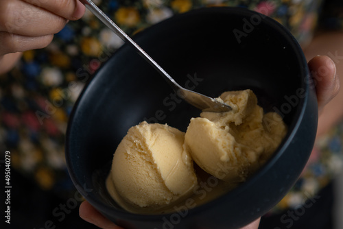Textura de helado cremoso de vainilla sobre un plato negro de cerámica 