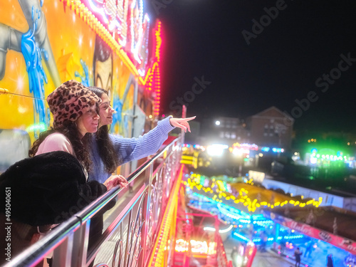 Friends gazing the horizon from the top of an aerial attraction at night fair © DavidMorillo