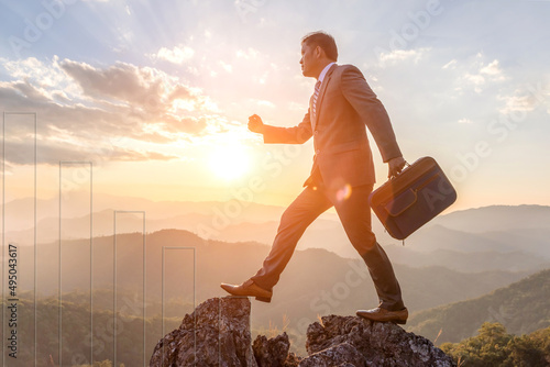 Successful business man, holding his business attache walking on the top of mountain. competition and leadership concept.