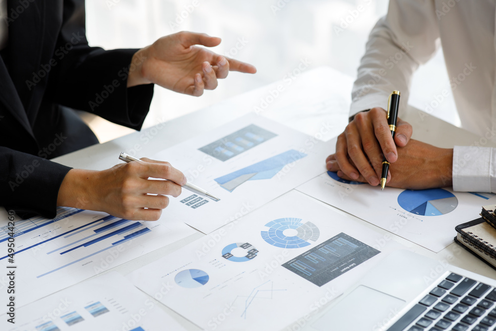 business documents on office table with smart phone and laptop computer and graph financial with social network diagram and three colleagues discussing data in the background business documents on office table with smart phone and laptop computer and graph financial with social network diagram and three colleagues discussing data in the background
