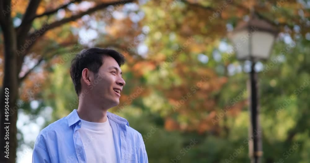 smiling handsome Asian young man at forest in autumn. Profile view. Slow motion smiling handsome Asian young man at forest in autumn. Profile view. Slow motion