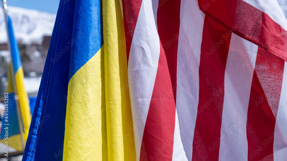 Close up of the Ukrainian flag and the flag of the United States side by side at a rally