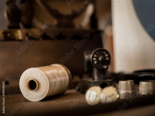 Needlework concept. Various sewing tools. Needles, scissors, buttons, spools, threads of different colors. Sewing accessories and fabric. Sewing threads, needles, pins, fabric on a wooden background.