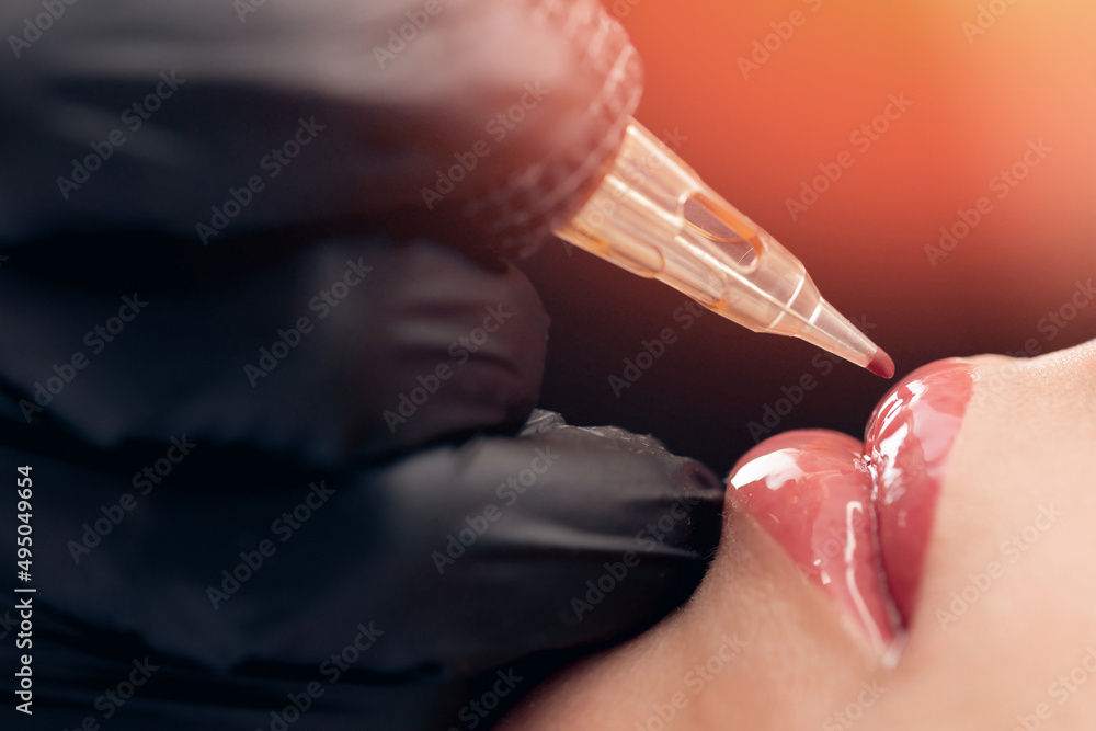 Macro photo of process of applying permanent makeup tattoo of red on lips woman Macro photo of process of applying permanent makeup tattoo of red on lips woman