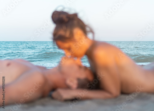 Topless beloved couple lying on beach and kissing