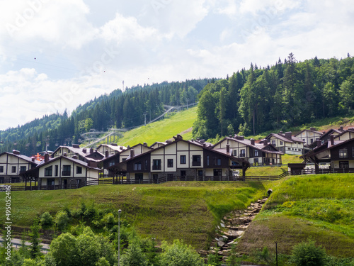 Scenic summer view of winter mountain ski resort with house cottages with forest and skiing slope in Bukovel, Ukraine. 