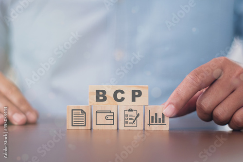 Business man puts the wooden cube with success icon BCP - business continuity Plan. acronym business concept. lettering illustration with icons for web banner, flyer, landing page