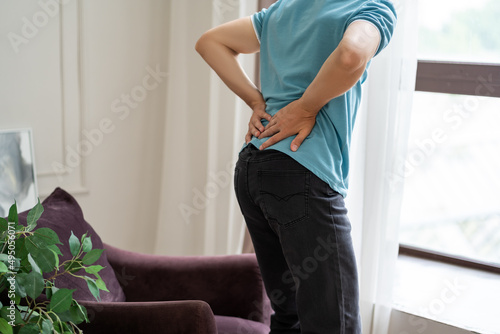 Back pain, kidney inflammation, man suffering from backache at home photo