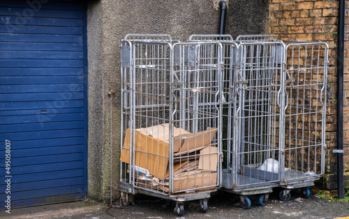 Cardboard trash collected in trolley roll cage at the back of a shop delivery area