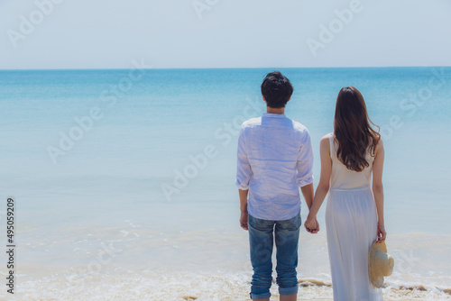 波打ち際で手をつなぐカップルの後姿