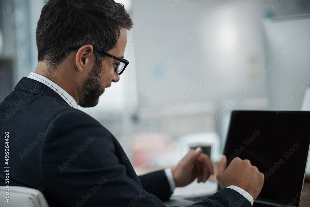 All part of the process of success. Shot of a young businessman working on a laptop in an office. All part of the process of success. Shot of a young businessman working on a laptop in an office.