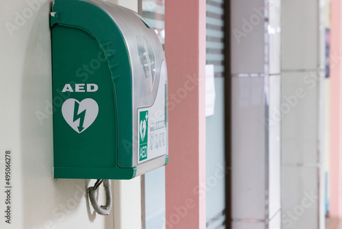 Automated external defibrillator in green box hang on wall in hospital. AED medical first aid device. photo