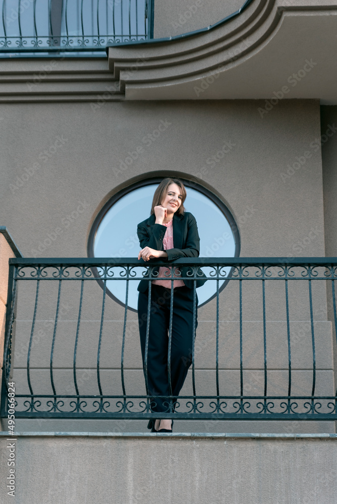 Smiling female boss in black pantsuit on the balcony. Middle-aged woman in formal business clothing. Smiling female boss in black pantsuit on the balcony. Middle-aged woman in formal business clothing.