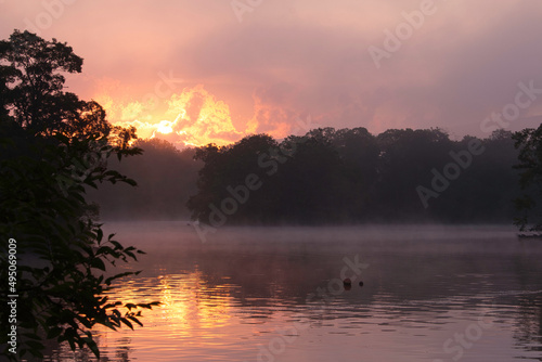 Fiery sunrise over a calm, misty lake