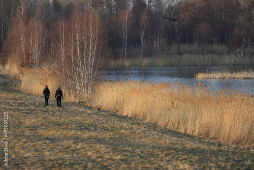Para młodych ludzi z psem na spacerze brzegiem jeziora.
