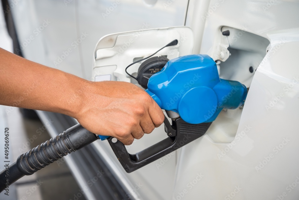 Hand holding blue fuel nozzle Car Gas Tank. Petroleum, energy and transportation concept. Hand holding blue fuel nozzle Car Gas Tank. Petroleum, energy and transportation concept.