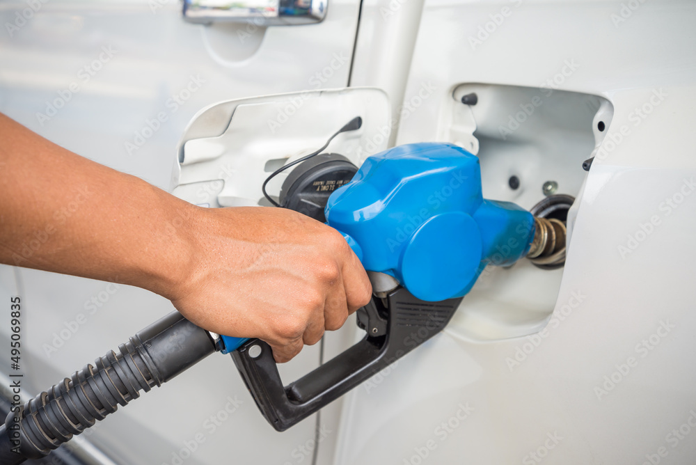 Hand holding blue fuel nozzle Car Gas Tank. Petroleum, energy and transportation concept. Hand holding blue fuel nozzle Car Gas Tank. Petroleum, energy and transportation concept.