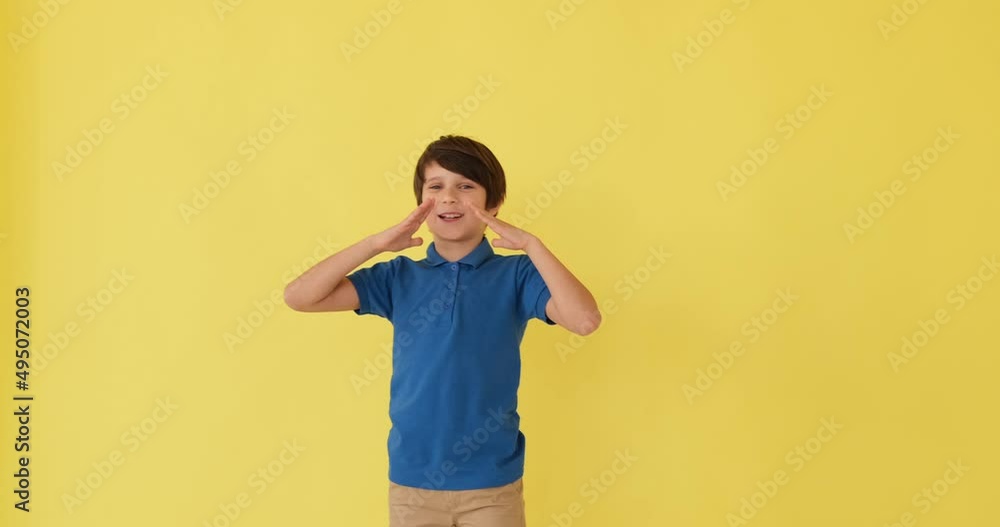 Boy shouting with hands cupped over yellow background Boy shouting with hands cupped over yellow background