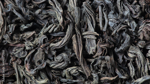 Dried black tea leaves as background.