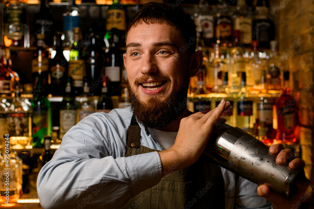 portrait of smiling bearded bartender with a shaker in his hands