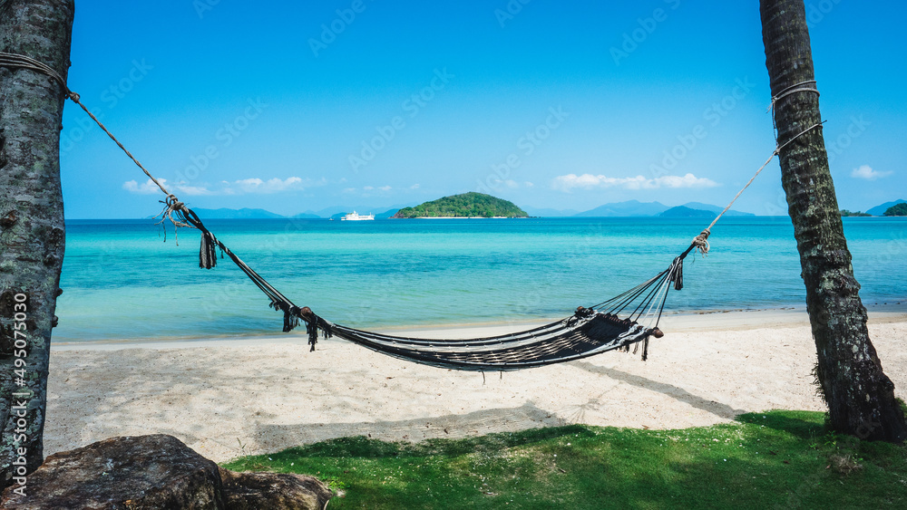 Fototapeta premium Relax beach hammock on peaceful white sand beach tropical island with clear turquoise sea against blue sky with Koh Kham view at horizon. Koh Mak Island, Trat, Thailand.