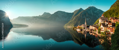 The iconic Austrian town Hallstatt in early morning light, a panoramic gorgeous landscape with the mountains, the houses and the teal sky reflected in the water of the lake photo