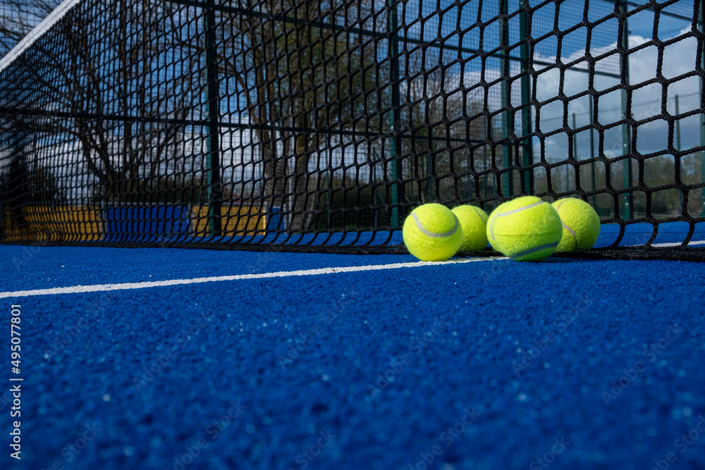 selective focus, five balls near the net of a blue paddle tennis court