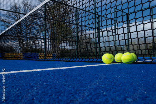 selective focus, five paddle tennis balls near the net of a blue paddle tennis court © Vic