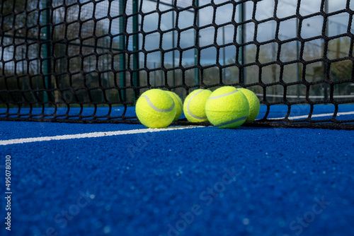 selective focus, five balls near the net of a blue paddle tennis court © Vic