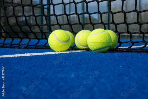 selective focus, five paddle tennis balls near the net of a blue paddle tennis court © Vic