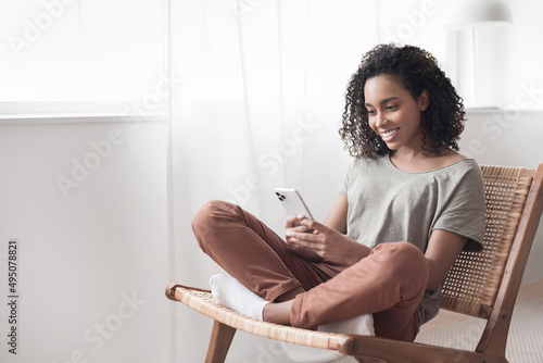 Young woman using smartphone at home. Student girl texting on mobile phone in her room. Communication, home work or study, connection, mobile apps, technology, lifestyle concept