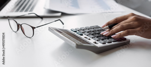Business woman working in finance accounting and analyse financial budget in office. Accountant calculate finance report using calculator and holding document, closeup, panoramic banner