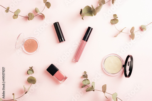 Cosmetics makeup items and eucalyptus branches on pink background. Flat lay beauty blogger, top view
