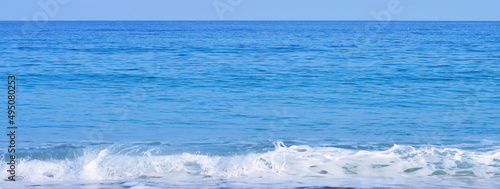 Seascape blue wallpaper - panoramic view on beach with white foam of surf, blue waves of water, horizon and sky