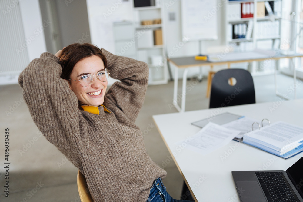 Ταπετσαρία young business woman with glasses sits at a desk with laptop and laughs into the