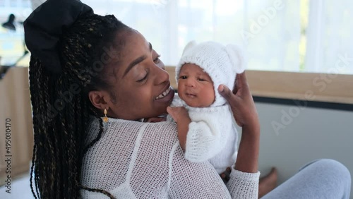 African American mother hold newborn baby on her shoulder and talk with take care the baby with love in bedroom of their house.