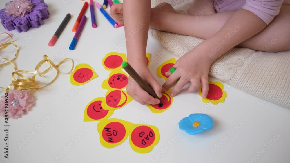 Child sitting on the floor and making fun Valentine cards, funny crafts Child sitting on the floor and making fun Valentine cards, funny crafts