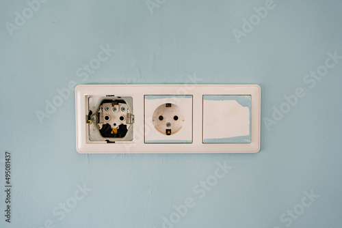 Photography faulty and sloppy triple socket on the blue wall
