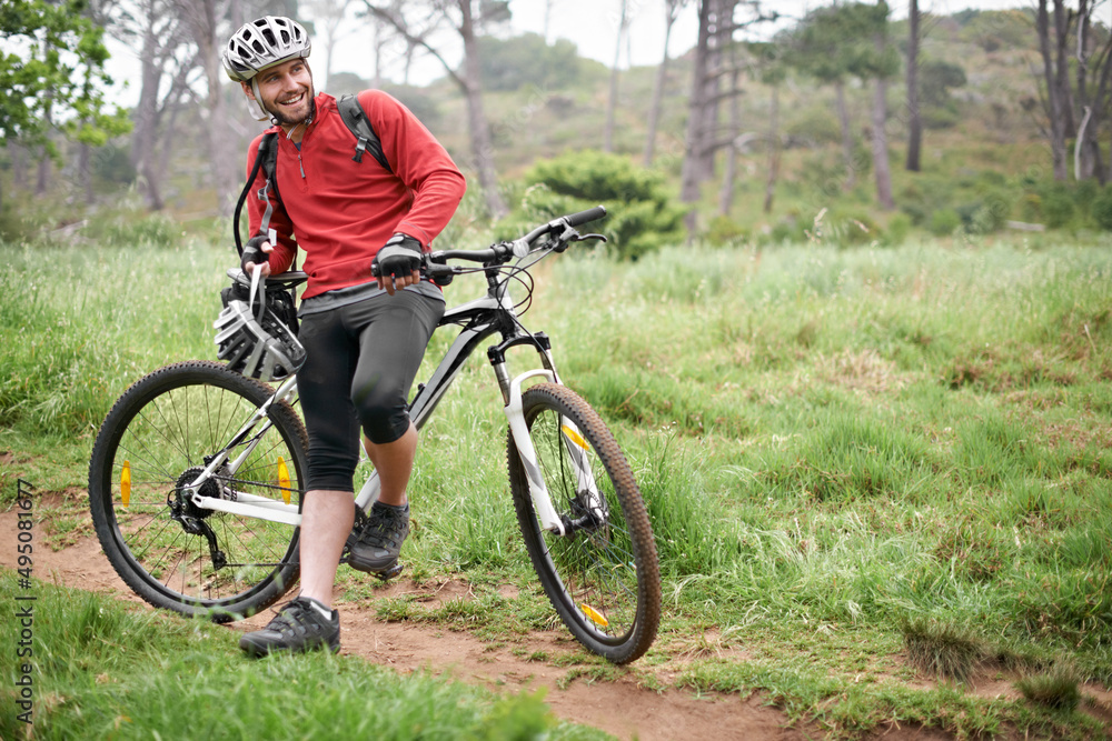 All I need is my bike and a trail. An attractive male cyclist leaning against his bike in the outdoors.