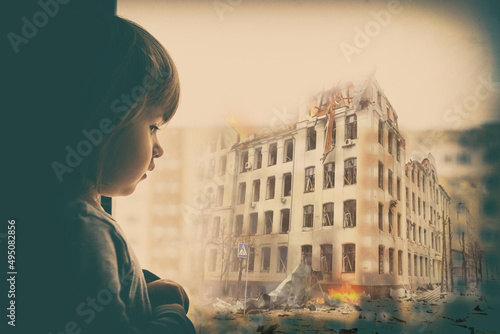 Sad baby girl on the background of the destroyed city. Destruction across Ukraine in the wake of Russian invasion. photo