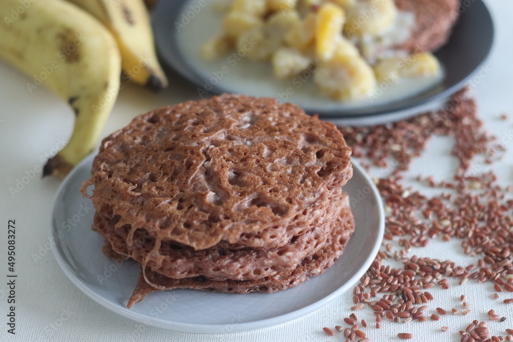 Red rice pancakes. Pancakes made of a fermented batter of red rice and coconut. Served with Ripe plantain stew