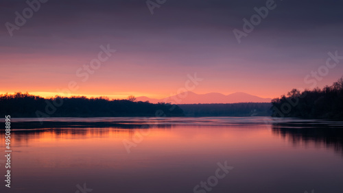 Dramatic sunset over Sava river with mountain in hazy glow - beautiful natural landscape © slobodan