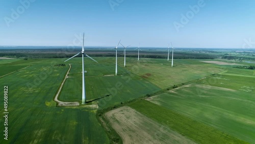 cinematic aerial drone camera shot you can see summer daytime panorama over the windmills farm. Shot captured in summer season somewhere in green meadow fields with blue sky. photo