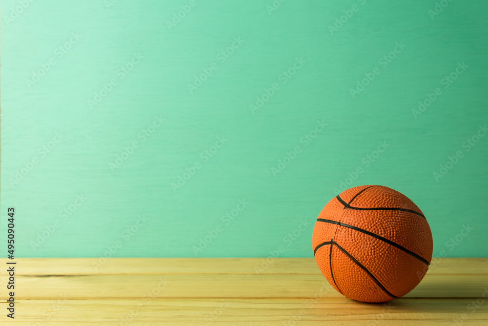 Basketball model over green wooden background copy space. Sport concept.