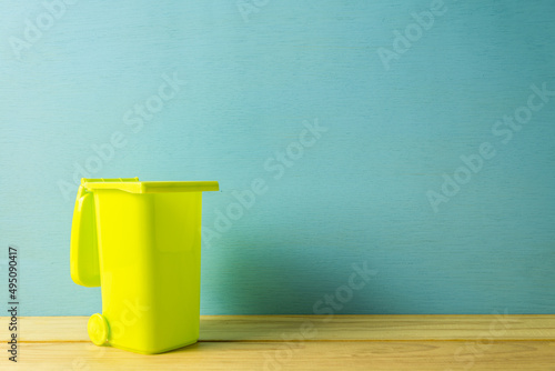 Model green open trash on wooden table over blue background copy space. Reduce, reuse, recycle, save the earth concept.