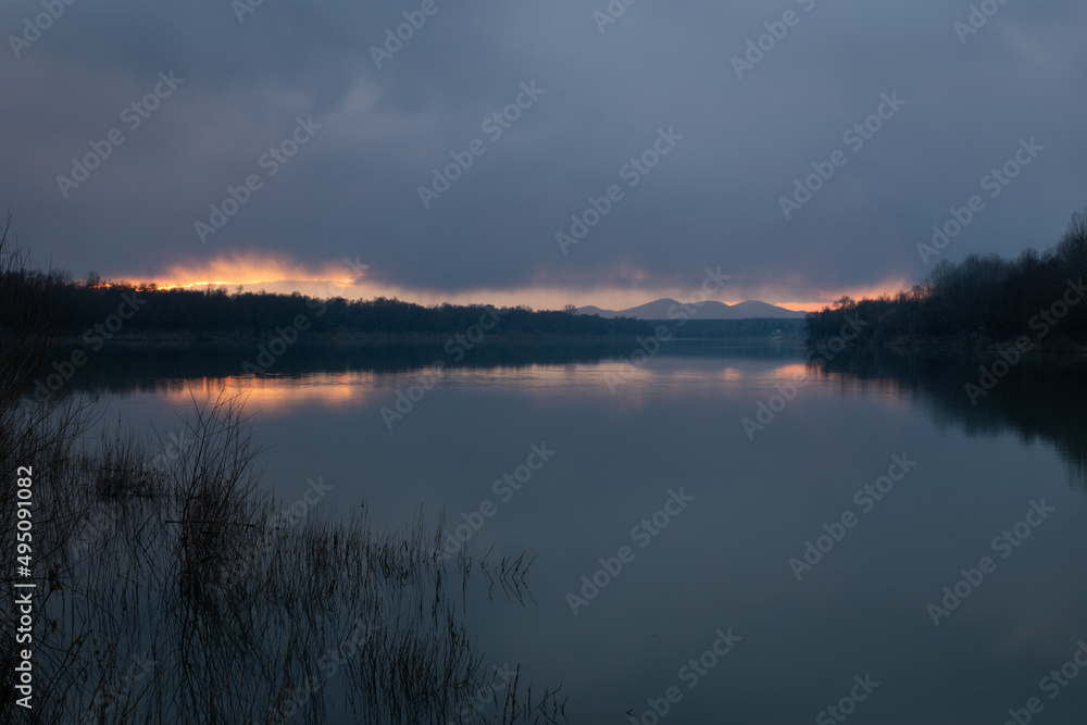 Landscape of River Sava and Motajica mountain with dark clouds at dusk