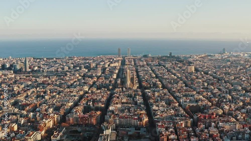 Aerial view on comfortable urban district of Barcelona, Eixample neigborhood. City blocks are separated by straight streets. Sagrada Familia cathedral is in centre of panorama, sea is on background photo