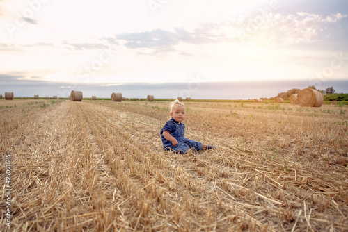  cute baby girl with a beautiful smile at gold wheat field.