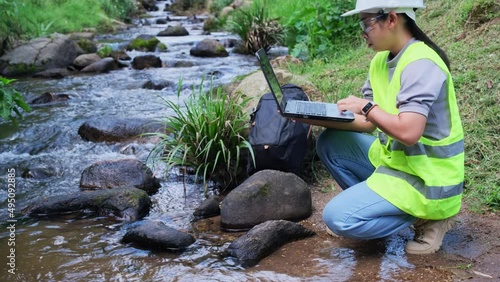 Environmental engineers inspect water quality at natural water sources and record the data on laptop computers. Woman scientist and environmental issues. World environment day concept.