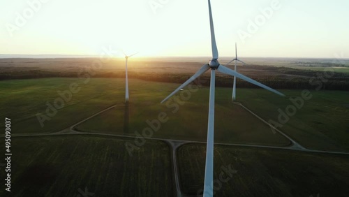 In this beautiful cinematic aerial drone camera shot you can see golden sunset panorama over the windmills farm. Shot captured in summer season somewhere in green meadow fields. photo